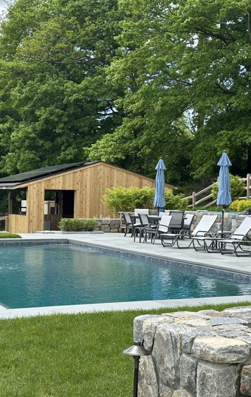 pool with lounge chairs and pool house in background
